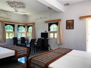 a room with two beds and a table and chairs at Gadh Ganesh Homestay in Udaipur