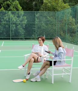 two women sitting in chairs on a tennis court at Ayara Kamala Resort & Spa in Kamala Beach