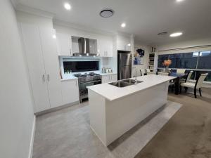 cocina con armarios blancos y encimera en 5 bedroom new house (no stairs), en Marsden Park