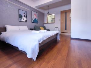 a large white bed in a room with a wooden floor at Ostay Kitahama Hotel Apartment in Osaka