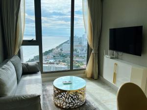 uma sala de estar com um sofá e uma mesa em frente a uma janela em Copacabana Jomtien Beach Condo 中天海滩寇芭酒店公寓 em Praia de Jomtien