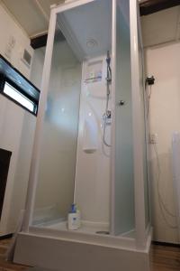 um chuveiro com uma porta de vidro na casa de banho em hostel+cafe たね 