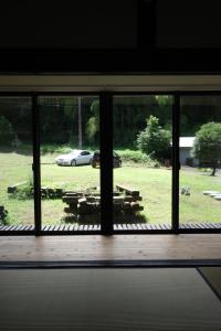 een raam met uitzicht op een veld en een auto bij hostel+cafe たね 