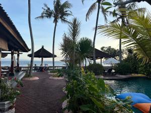 ein Resort mit einem Pool, Palmen und dem Meer in der Unterkunft Pondok Bambu Resort - 5 Stars Padi Dive Centre in Candidasa