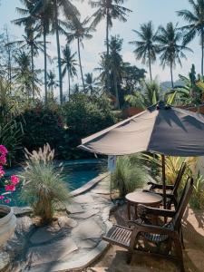 un tavolo con ombrellone accanto a una piscina di Villa Paradiso a Senggigi