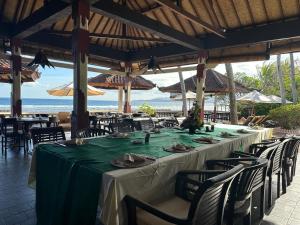 una mesa larga en un restaurante con la playa en el fondo en Pondok Bambu Resort - 5 Stars Padi Dive Centre, en Candidasa