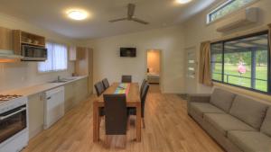 a kitchen and living room with a table and a couch at Yarra Holiday Park in Stuarts Point