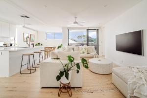 a living room with white furniture and a kitchen at SILK - Lustrous Vacation Awaits 400m to the Beach in Coolum Beach