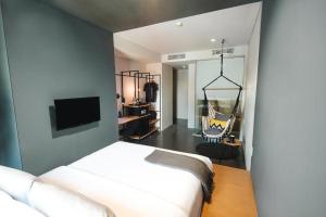 a bedroom with a bed and a room with a tv at The Hammock Hotel Ben Thanh in Ho Chi Minh City