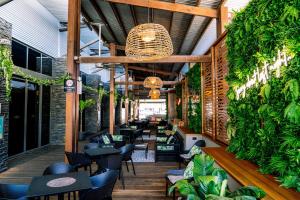 a restaurant with tables and chairs and plants at Gilligan's Hotel & Resort Cairns in Cairns