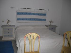 una camera da letto con un letto con due tavoli e due sedie di Casa Vacanze Il Pino a Cannigione