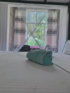 a bed with a rolled up towel on top of it at Surf Home Stay Hiriketiya in Hiriketiya