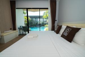 a bedroom with a large white bed and a pool at Guuden Huahin Hotel in Hua Hin
