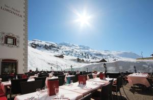 a restaurant with tables and chairs in front of a mountain at Sporthotel Lorünser in Zürs am Arlberg