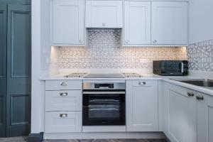 a white kitchen with white cabinets and a stove top oven at Supersized Studio in Chester in Chester