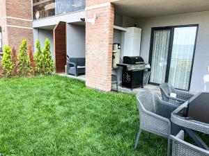 un patio trasero con parrilla, sillas y césped en Luxury Apartment with Garden right by sea, en Mudanya