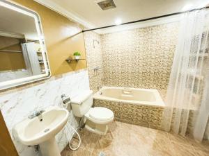 a bathroom with a toilet and a sink and a tub at Miramar Hotel in Manila