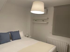 a bedroom with a bed with blue pillows and a light at C1 Madrid, Zona exclusiva in Madrid