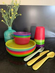 a table with colorful plates and utensils on a table at Panda's Patch Dunsborough in Dunsborough