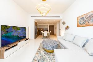 a living room with a white couch and a flat screen tv at Brand New 2BR Apt with Palm Views and Private Beach - High Floor in Dubai