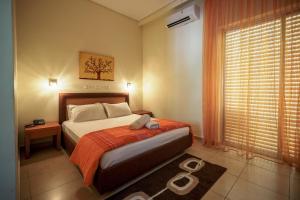 1 dormitorio con 1 cama con manta naranja y ventana en Hotel Panorama, en Kalamata