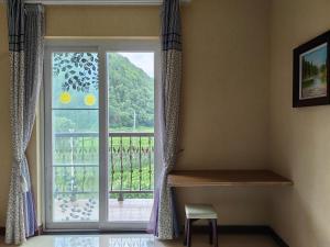 een kamer met een raam met uitzicht op een balkon bij Valley Oasis Villa in Enshi