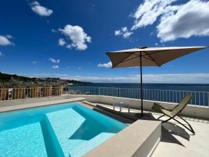 a swimming pool and an umbrella on a balcony with the ocean at Marinaia Gran Vista Mare in Marittima