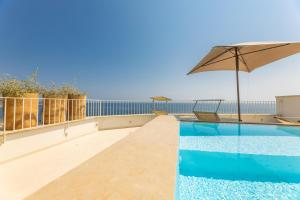 een zwembad met een parasol en uitzicht op de oceaan bij Marinaia Gran Vista Mare in Marittima