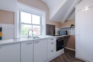 a white kitchen with a sink and a window at 2-Bed Victorian Oasis in Chester in Chester