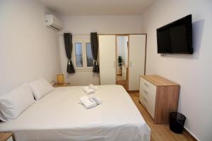 a bedroom with a white bed and a flat screen tv at Blue Lagoon 3 in Kavala