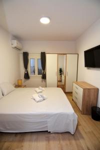 a bedroom with a large white bed and a flat screen tv at Blue Lagoon 3 in Kavala