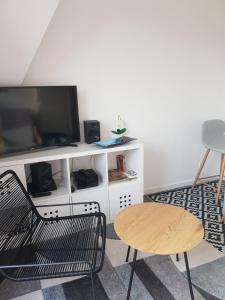 uma sala de estar com uma televisão, uma cadeira e uma mesa em Appartement Liza 2 pièces Vue Mer à Cabourg em Cabourg