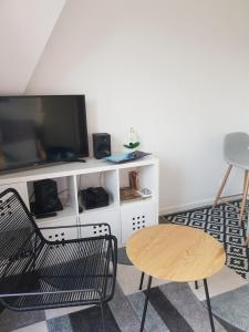 a living room with a tv and a chair and a table at Appartement Liza 2 pièces Vue Mer à Cabourg in Cabourg