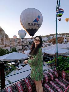 een vrouw die voor een heteluchtballon staat bij Vintage Cave House Hotel in Goreme