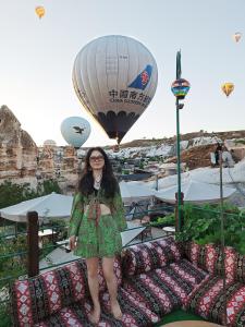 una mujer parada en una cama frente a un globo de aire caliente en Vintage Cave House Hotel en Göreme