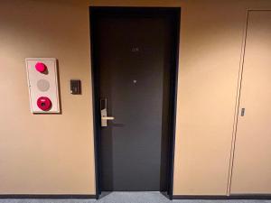 czarne drzwi z czerwonym światłem stopu obok w obiekcie Cypressinn Tokyo w Tokio