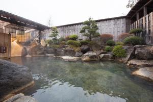 una piscina de agua con rocas en un jardín en Kouunsou en Nasushiobara