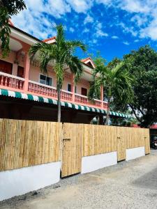 a fence in front of a house with palm trees at Casa Cactus in Bang Rak Beach
