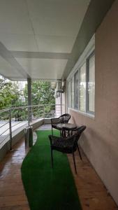 einen Balkon mit 2 Stühlen und einem Tisch auf einem grünen Teppich in der Unterkunft “Simbad” guest house in Jalal-Abad