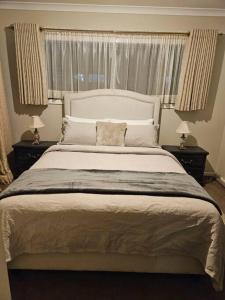 a bedroom with a large white bed with two night stands at Tranquil home in Point Cook. in Point Cook