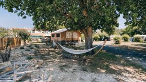 a hammock sitting under a tree in a yard at Camping La Prée in Les Portes