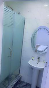 ein Bad mit einer Dusche, einem Waschbecken und einem Spiegel in der Unterkunft Thistle Greens Apartment in Ikeja