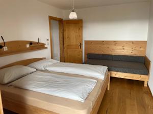 a bedroom with two beds and a bench at Oberfahrerhof in San Genesio Atesino