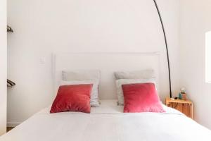 2 cuscini rossi posti sopra un letto bianco di Luxe-Avontuur in een Romantische Cabin in het Bos a Stekene