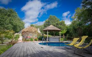 a deck with two chairs and an umbrella next to a pool at Gîte du Placello, piscine jacuzzi et sauna in Quistinic