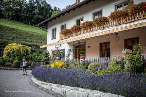 a woman standing in front of a house with flowers at Gourmetbauernhof Mentebauer in Gmünd in Kärnten