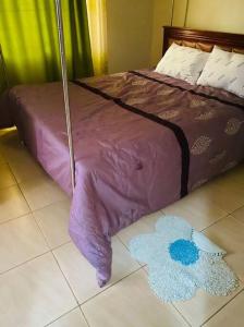 Bett mit lila Daunendecke auf dem Boden in der Unterkunft Orchard Home Homestay in Mbarara