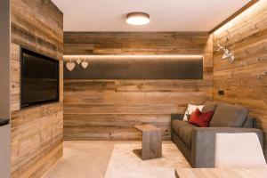ein Wohnzimmer mit Holzwänden, einem Sofa und einem TV in der Unterkunft Obergasserhof Apt Tiroler in Riscone
