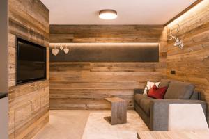 a living room with wooden walls and a couch and a tv at Obergasserhof Apt Tiroler in Riscone