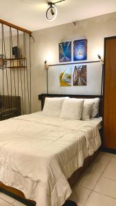 Santa RosaにあるCasa Cabilao Staycationのベッドルーム1室(壁に絵画が飾られた白い大型ベッド1台付)